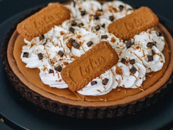 Scrumptious Biscoff tart topped with whipped cream and cookie pieces, a gourmet pastry delight.