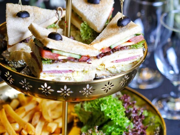 Delicious club sandwiches elegantly presented with fries and salad garnish on a golden platter.